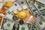 Fintechs e soluções em Stablecoins ilustradas com moedas tradicionais, bitcoin e cédulas em diferentes moedas.