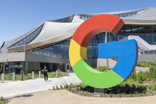 Imagem da fachada do Google com a instalação do logotipo gigante em frente ao prédio de arquitetura moderna, em um dia ensolarado.