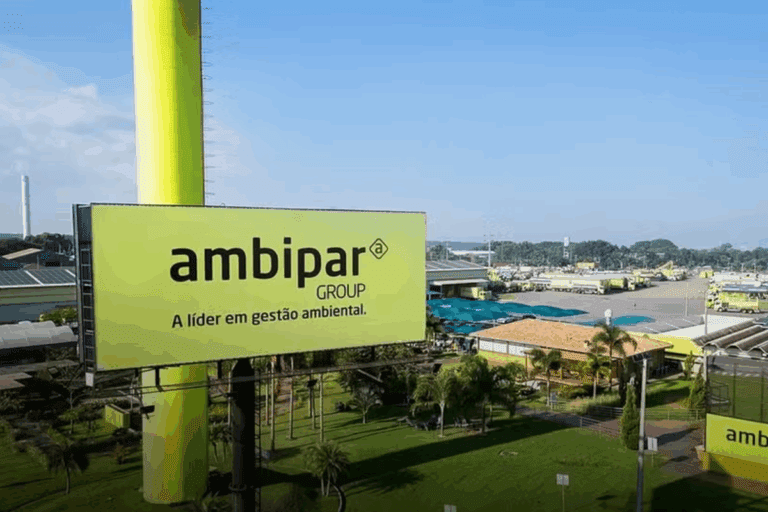 Painel publicitário da Ambipar Group em um ambiente externo, promovendo gestão ambiental, com árvores e instalações ao fundo, sob céu claro.