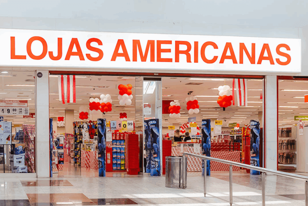 Entrada da loja americanas com decoração de balões nas cores vermelho, branco e laranja, na fachada com destaque para o nome Lojas Americanas.