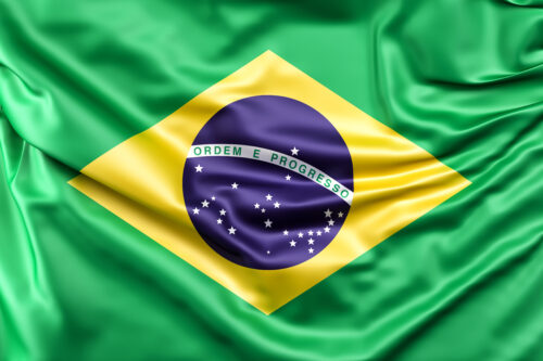 Bandeira do Brasil deitado em tecido com efeito de seda, mostrando suas cores verde, amarelo, azul e branco, representando o país.