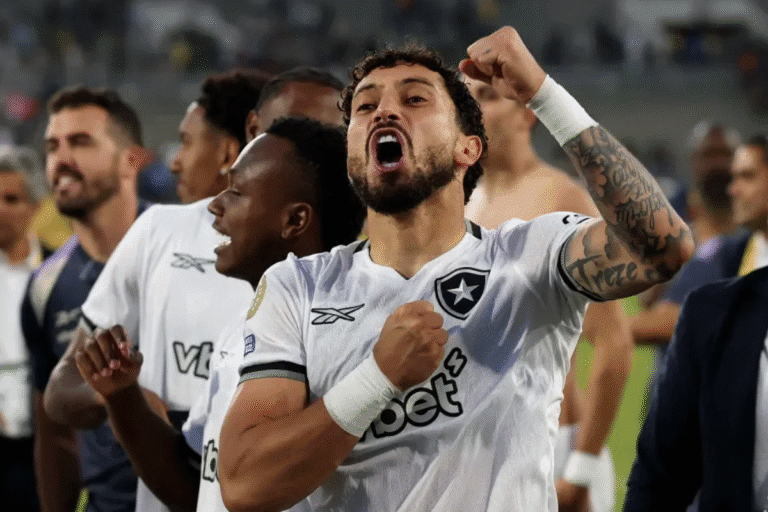 Jogadores de futebol comemorando uma vitória, destacando-se um atleta com expressão de celebração, rosto emocionado e braço levantado, em campo