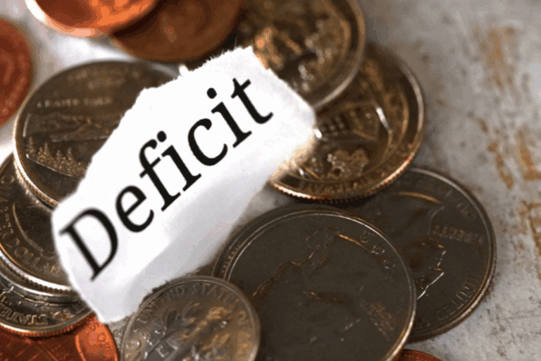 Moedas de centavos de euro e uma folha de papel com a palavra 'Déficit' escrita, simbolizando preocupação financeira e déficit econômico.