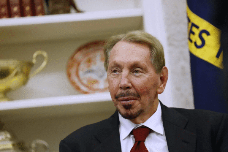 Larry Ellison, usando terno e gravata, em ambiente com decoração de prateleiras e bandeira ao fundo, em uma foto otimizada para SEO.