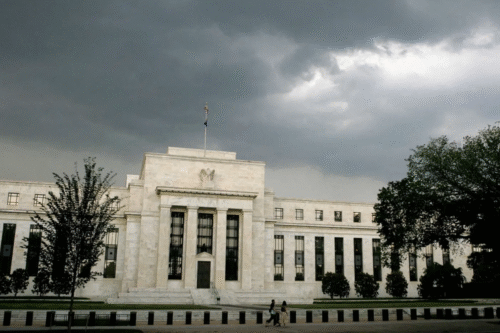 Prédio da sede do Federal Reserve em Washington, D.C., sob céu nublado e escuro.