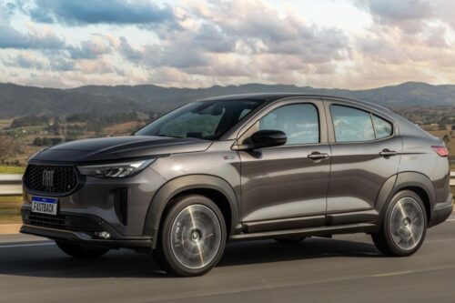 Fiat Fastback preto em movimento na rodovia com cenário de montanhas ao fundo, destacando seu design moderno e aerodinâmico.