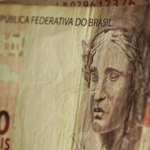 Close de uma nota de 10 reais com um rosto esculpido em relevo. O texto diz "República Federativa do Brasil".