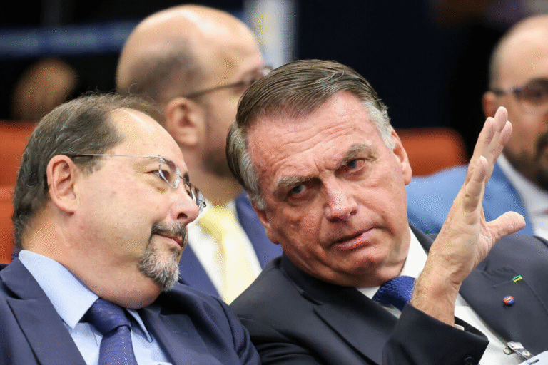 Imagem de Jair Bolsonaro em um encontro político discutindo com colegas ao seu lado, todos em traje formal e com expressão séria, ambiente de reunião pública.