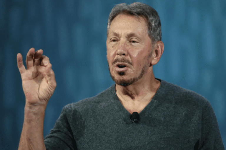 Larry Ellison com expressão facial séria e gesticulando com a mão, em fundo azul, durante uma palestra ou entrevista, relacionado à inovação em tecnologia.