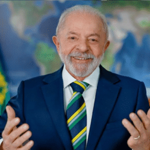 Imagem de um homem idoso sorridente, usando terno azul e gravata listrada, em um ambiente com bandeira do Brasil ao fundo, simbolizando liderança e governança.