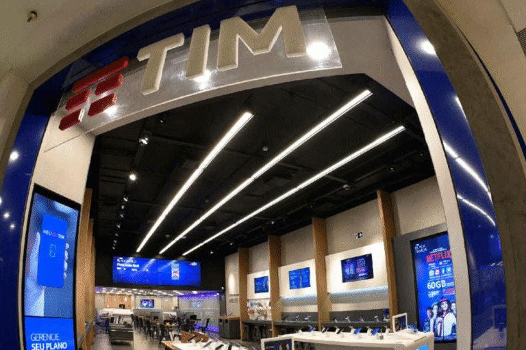Interior de uma loja TIM com displays digitais, balcões de atendimento e ambiente moderno, focado em venda de planos e dispositivos móveis.