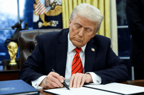 Imagem do presidente Donald Trump assinando um documento no escritório com uma expressão séria, simbolizando liderança e política nos Estados Unidos.