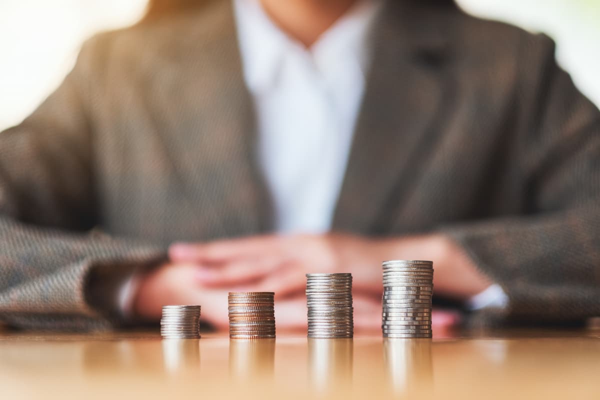 Investimento com liquidez diária representado por pilhas de moedas em crescimento sobre a mesa.