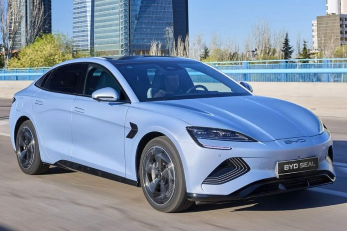 Foto de um carro elétrico BYD Seal em movimento pelas ruas de uma cidade com prédios modernos ao fundo.