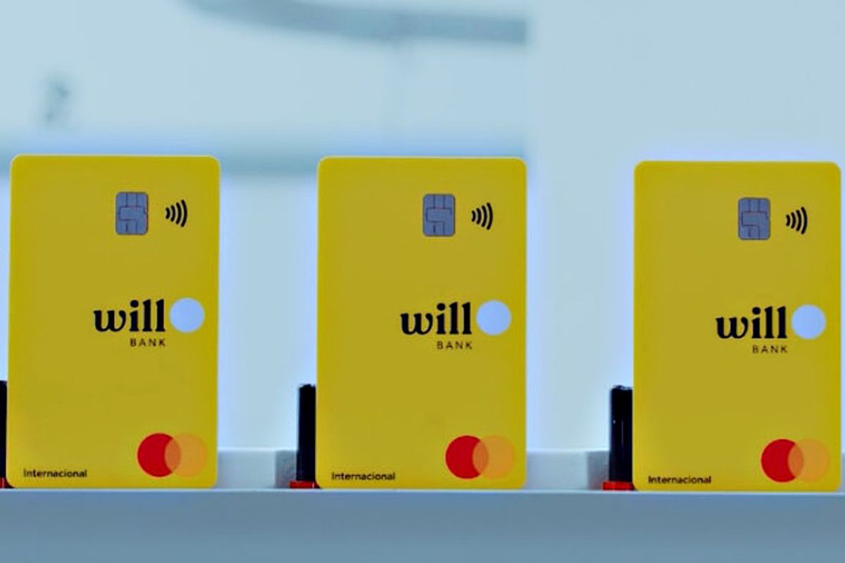Três cartões de débito ou crédito amarelos com a marca 'Will Bank' em uma superfície, utilizados para pagamento digital em estabelecimentos comerciais.
