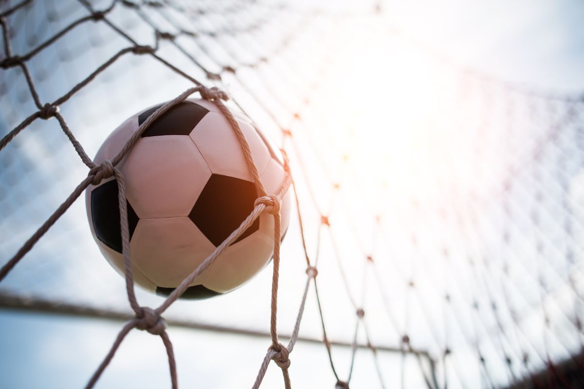 Bola de futebol presa na rede de uma quadra ao pôr do sol.do esporte na recreação e atividade física.