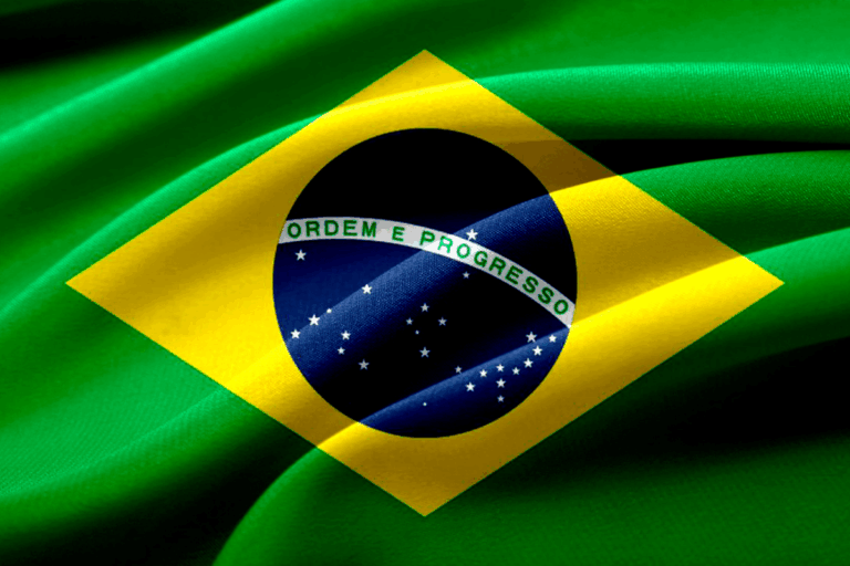 Bandeira do Brasil com fundo de tecido verde. Destaca o símbolo nacional com estrelas brancas, um círculo azul e faixa com a inscrição 'Ordem e Progresso'.