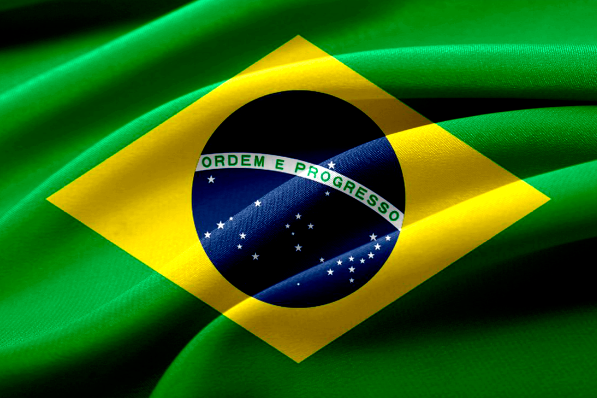 Bandeira do Brasil com fundo de tecido verde. Destaca o símbolo nacional com estrelas brancas, um círculo azul e faixa com a inscrição 'Ordem e Progresso'.