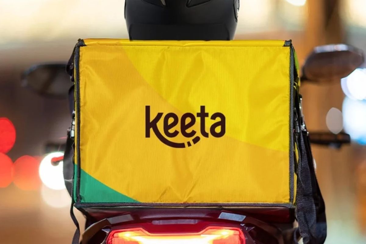 Entrega de comida no sistema de delivery Keeta, com mochila térmica amarela instalada na motocicleta