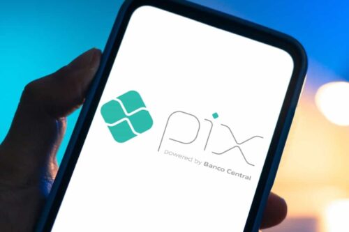 Aplicativo Pix no celular, método de pagamento digital do Banco Central do Brasil, com fundo de cores azul e laranja. Ótimo para transferência de dinheiro rápida.