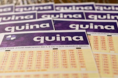 Cartelas de raspadinha da loteria Quina com números destacáveis e foco na marca Quina em fundo roxo.