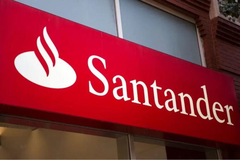 Loja do banco Santander com logotipo vermelho e branco, destaque para o nome Santander e símbolo de uma folha de bordo estilizada, em ambiente urbano.