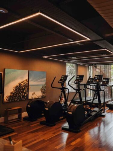 Sala de treinos moderna da SIX Sport Life com esteiras, bicicletas e design sofisticado em madeira.