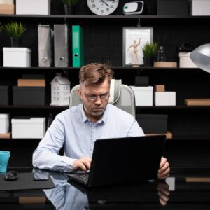 Homem trabalha concentrado em seu notebook em um escritório moderno, representando o conceito de microshifting.