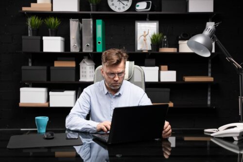 Homem trabalha concentrado em seu notebook em um escritório moderno, representando o conceito de microshifting.