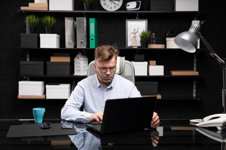 Homem trabalha concentrado em seu notebook em um escritório moderno, representando o conceito de microshifting.