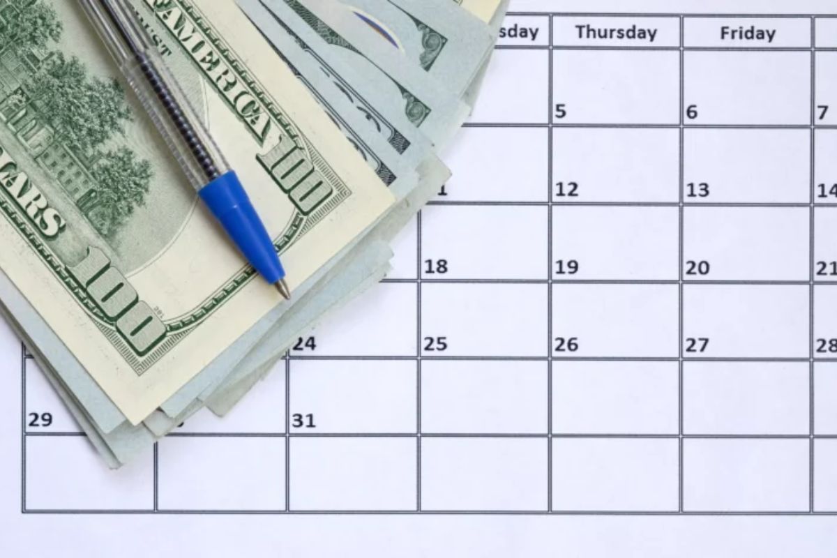 Planejamento financeiro usando calendário, dinheiro em notas de dólar e caneta