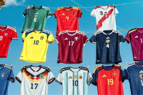 Uma coleção de uniformes da Copa do Mundo 26 de diversas seleções nacionais (incluindo Suécia, Alemanha, Argentina, Espanha e outras), feitas pela Adidas penduradas em um varal com grampos de roupa, sob um céu azul claro.