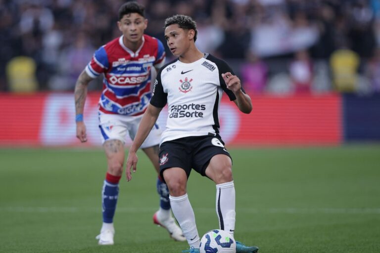 Dieguinho em ação durante partida, concentrado na bola, com adversário ao fundo em estádio cheio, usando uniforme do time Corinthians.
