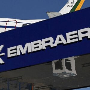 Fachada de uma loja da Embraer, fabricante brasileira de aeronaves, com destaque para o logotipo em letras brancas e fundo azul, visível no centro da imagem.