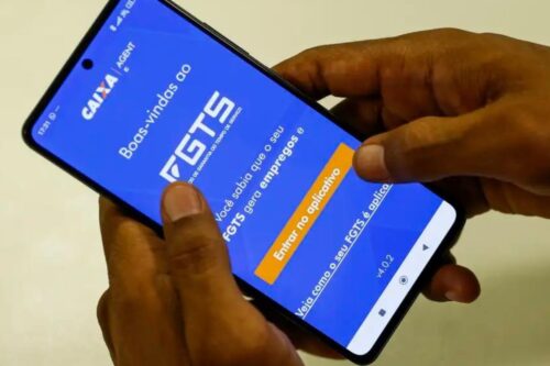 Pessoa usando um smartphone para acessar o site do FGTS, destacado por uma tela azul com texto explicativo para facilitar o acesso ao benefício.