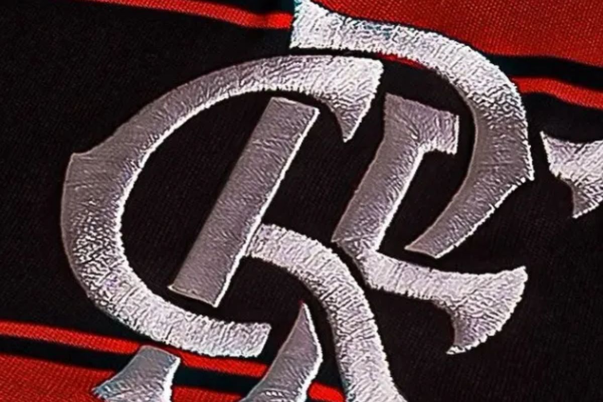 Close-up do monograma do clube, que exibe as letras "CRF" (sigla para Clube de Regatas do Flamengo), bordadas em um tecido com as tradicionais listras vermelhas e pretas do time.