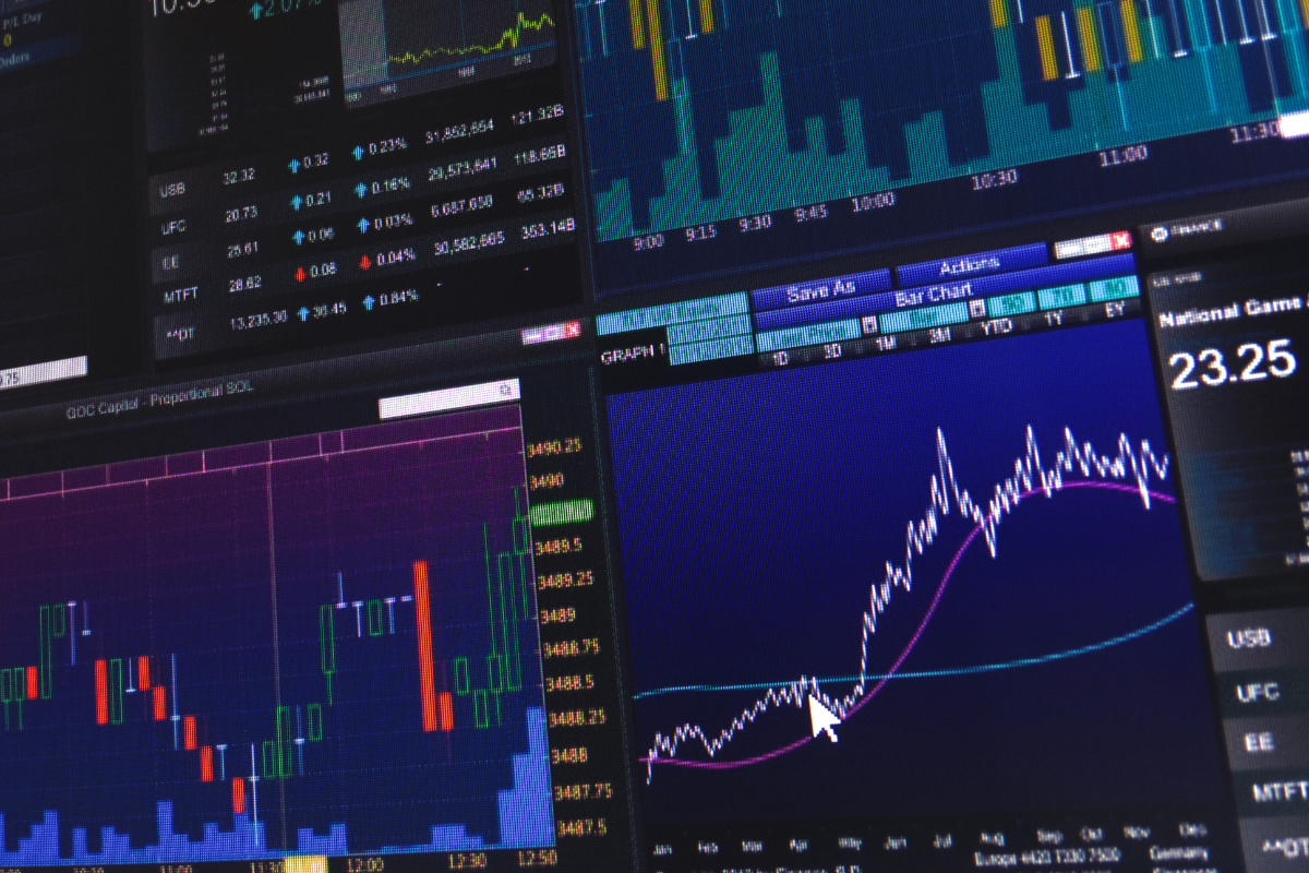 Gráficos de análise financeira e dados de mercado em telas de computador, representando negociação de ações e investimentos no mercado financeiro.