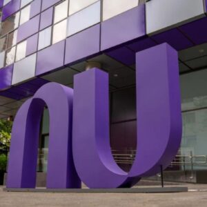 Uma escultura grande e roxa das letras 'nu', o logotipo da Nubank, em frente ao edifício de escritórios da empresa, que também tem detalhes em roxo e espelhado.