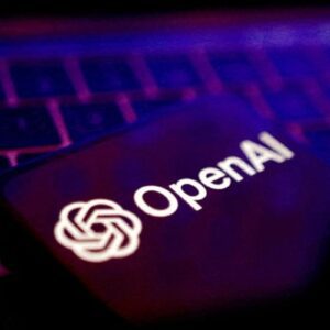 O logotipo e o nome 'OpenAI' em branco exibidos na tela escura de um celular ou dispositivo, posicionado sobre um teclado de computador com iluminação em tons de roxo e rosa.