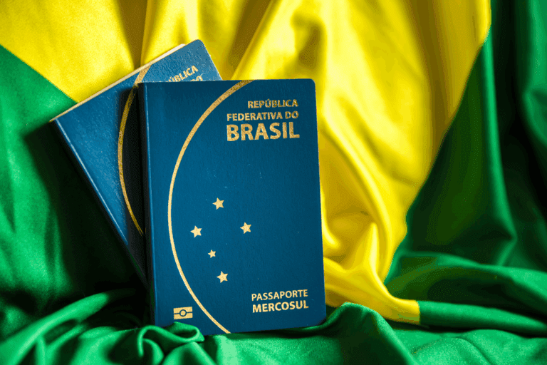 Passaporte da República Federativa do Brasil em destaque sobre uma bandeira do Brasil, com cores verde, amarelo e azul ao fundo.