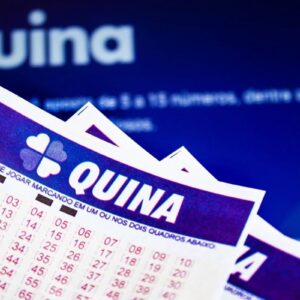 Bilhetes da loteria brasileira Quina, com o logotipo de trevo de quatro folhas e números para marcação, empilhados sobre um fundo azul escuro com a palavra "Quina" em destaque e embaçada.