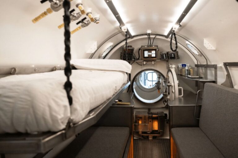 Interior de um espaço confinado e cilíndrico, semelhante a um submersível ou câmara de descompressão.