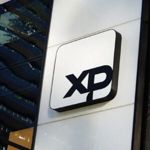 Placa com o logotipo preto da XP montada na fachada externa de um edifício moderno