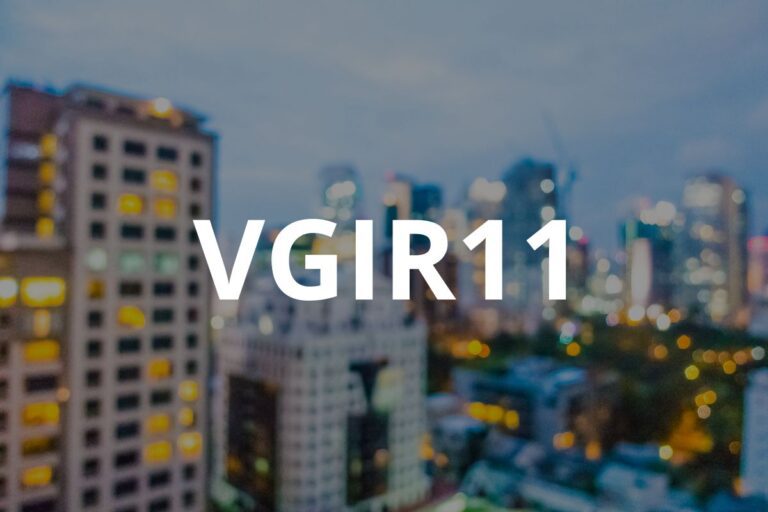 Ticker "VGIR11" em branco e em negrito sobre uma foto desfocada de edifícios altos de uma cidade durante a noite ou ao anoitecer.