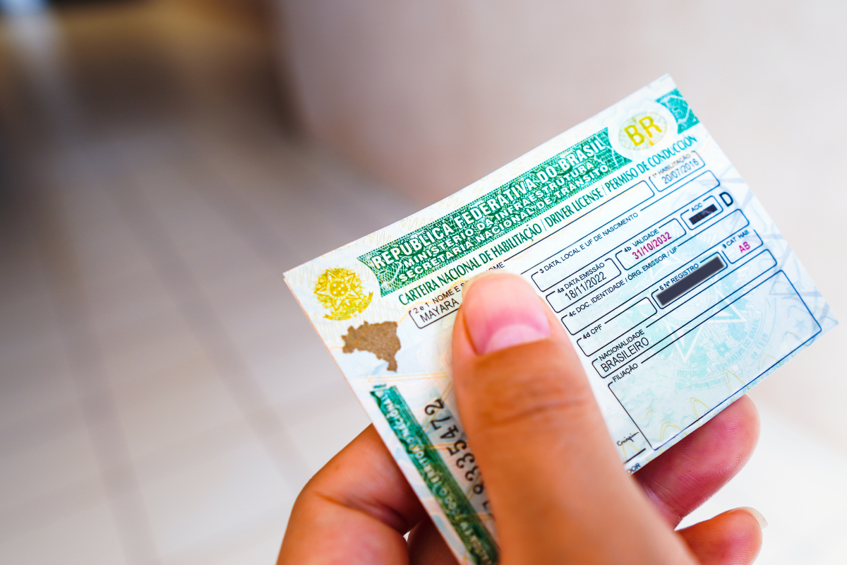 Foto de uma mão segurando a Carteira Nacional de Habilitação (CNH)