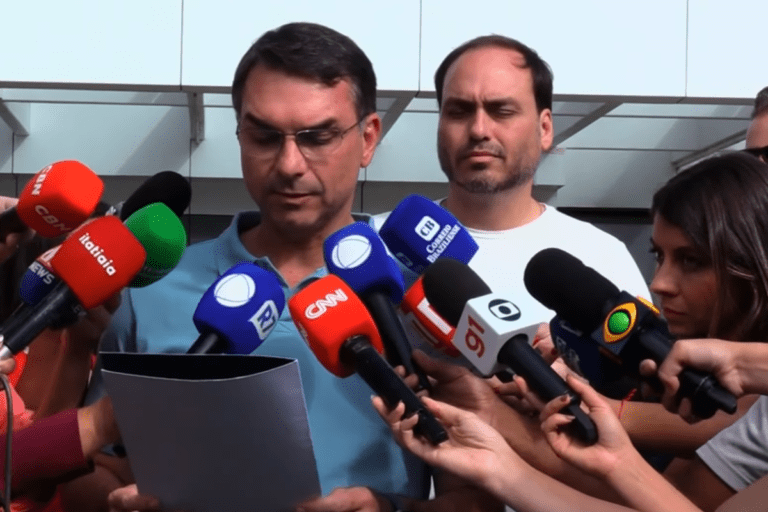 Flávio Bolsonaro lê à imprensa a carta escrita por Jair Bolsonaro que confirma sua pré-candidatura, ao lado do irmão Carlos.