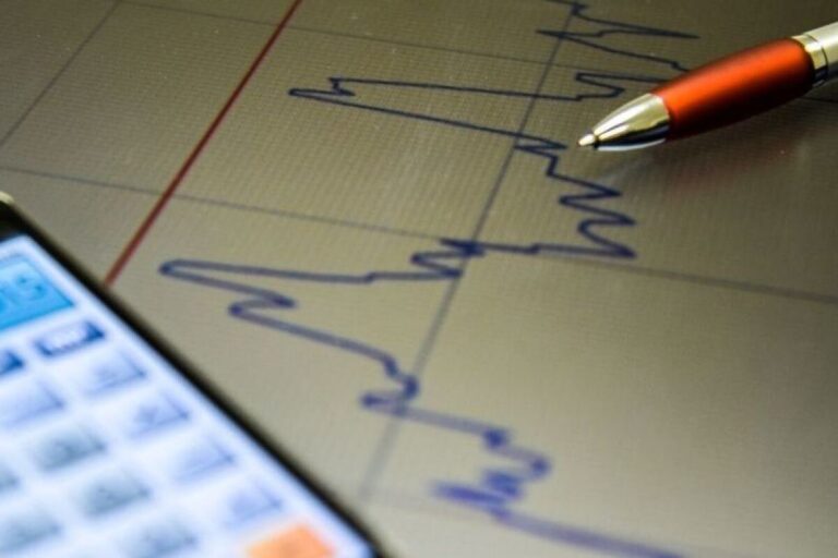 A imagem em close-up mostra um gráfico de linha azul, flutuante e de alta resolução, desenhado sobre uma superfície escura que se assemelha a uma tela ou papel.