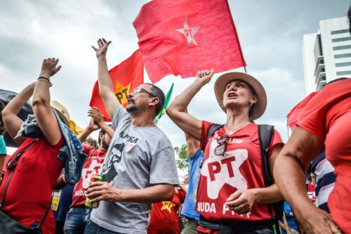 Fotografia em ângulo baixo de manifestantes em um ato político do Partido dos Trabalhadores (PT).