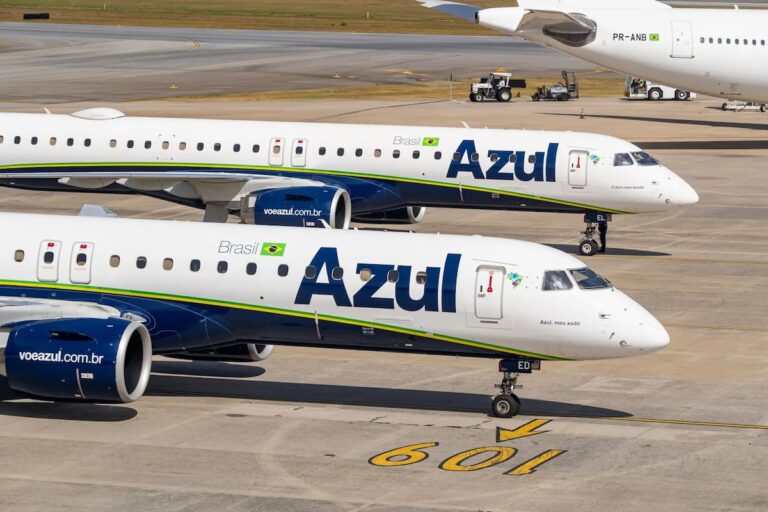 Aviões da companhia aérea Azul (AZUL4) estacionados no pátio do aeroporto, com pintura azul e branca e bandeira do Brasil.