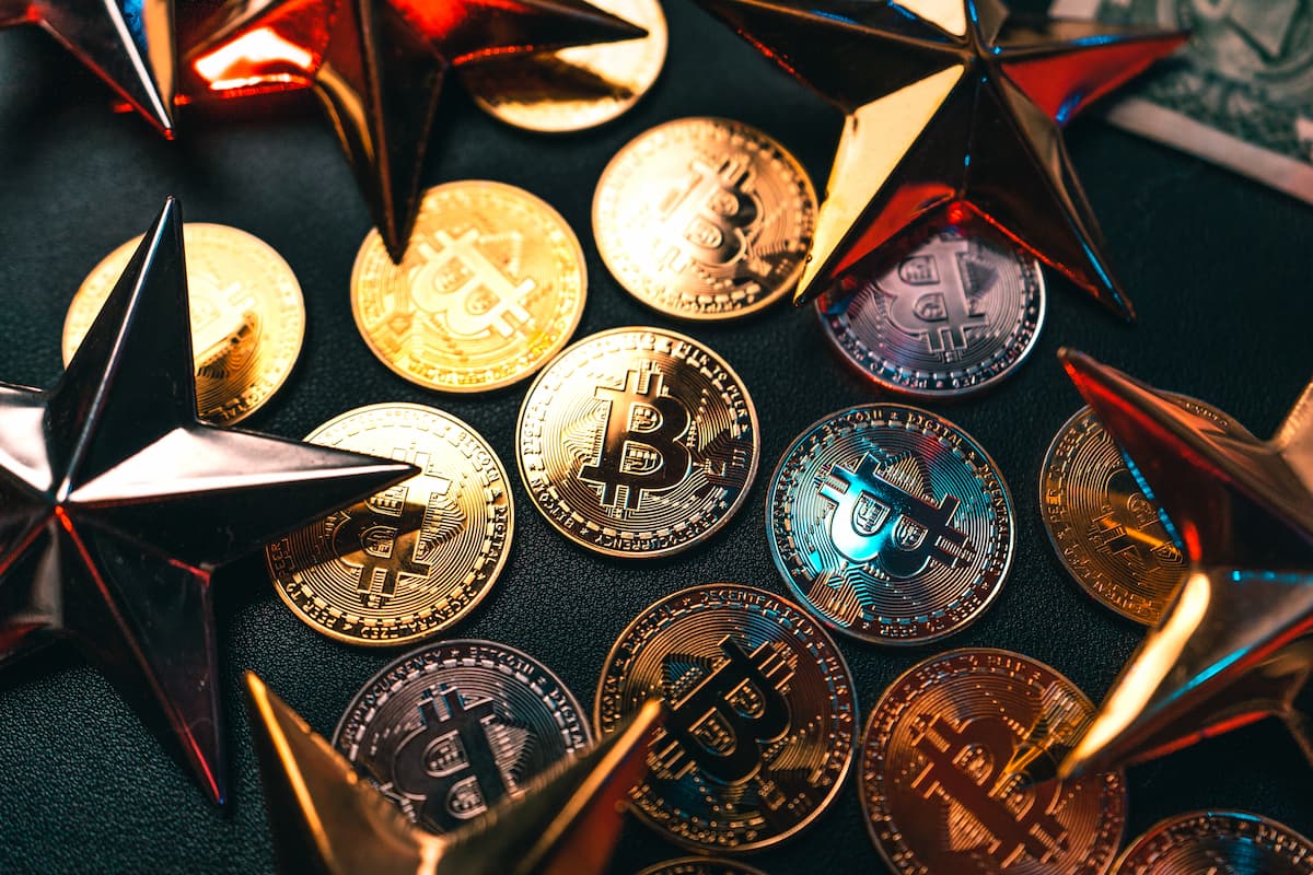 Moedas físicas de Bitcoin sobre fundo escuro representando criptomoedas para investir em dezembro de 2025.